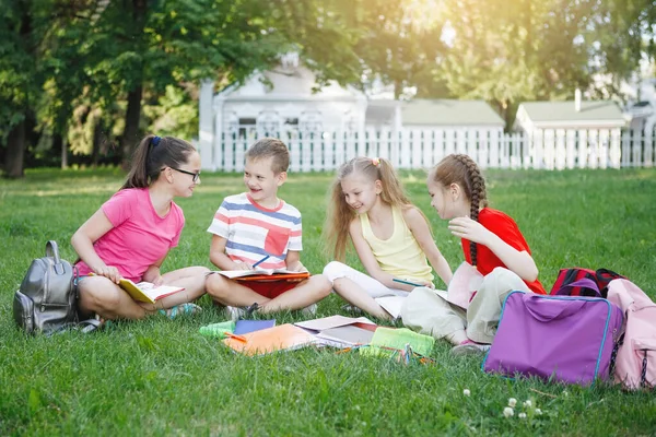 Four children sitting on the green grass. Royalty Free Stock Photos