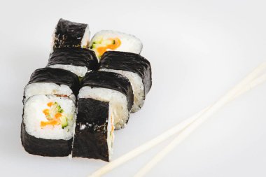 Japon yılan balığı suşileri beyaz arka planda çubuklarla yuvarlanıyor.