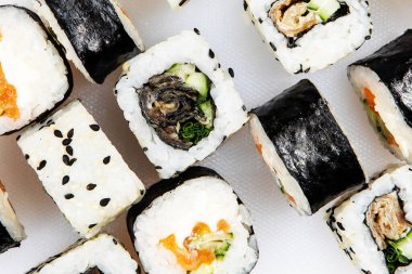 Japon suşi ruloları hazırla, beyaz arka planda susam tohumlu somon balığı. Üst görünüm.
