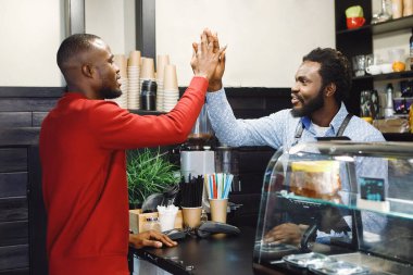 Barista Afrikalı Amerikalılar ve müşterileri barda birbirlerini selamlıyorlar..