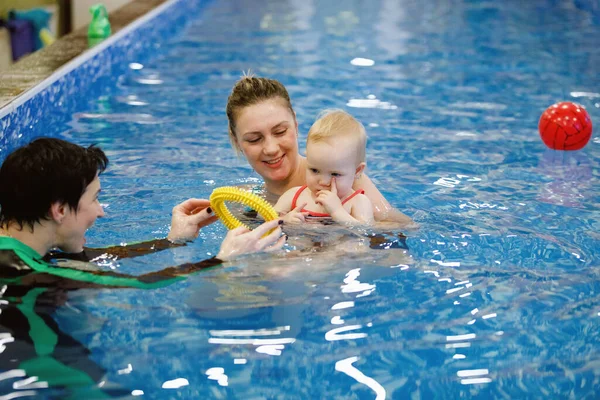 Woman child trainer and toddler swim and study in blue water pool
