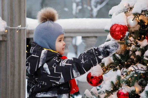 Pofuduk Şapkalı Çocuk Dışarıdaki Noel Ağacındaki Oyuncaklara Bakıyor — Stok fotoğraf