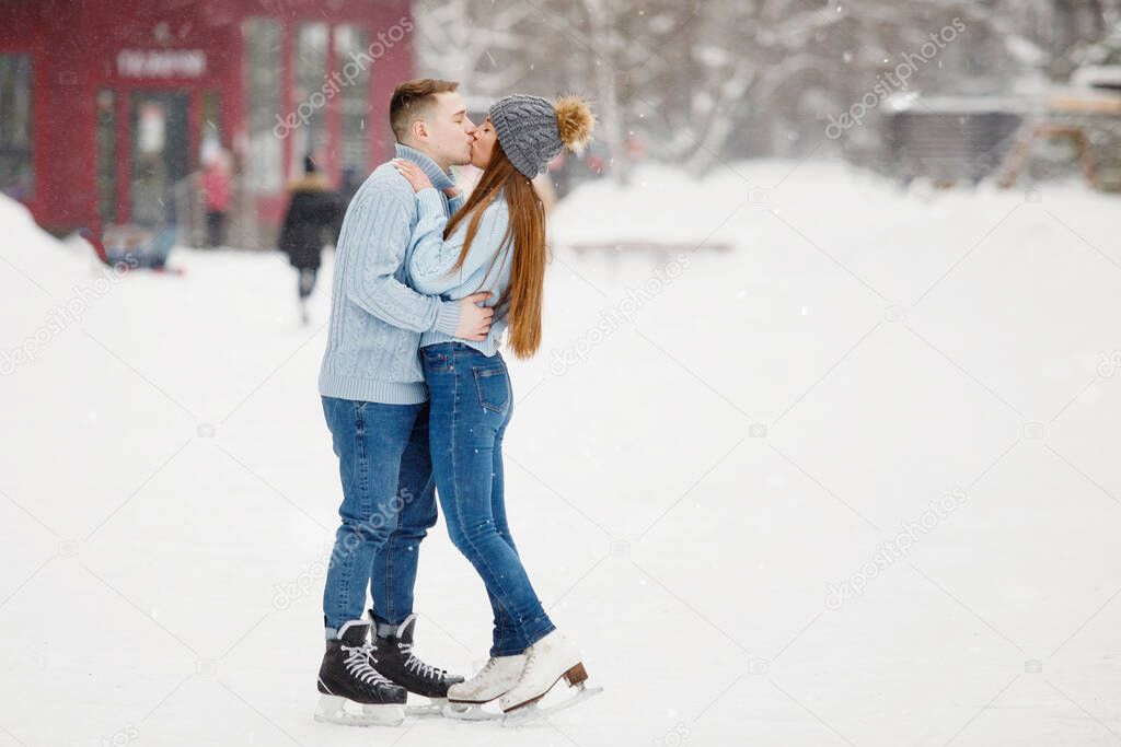 Young Couple man and woman kissing on ice skating rink in winter.