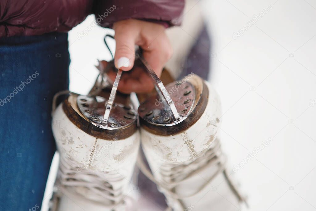 Girl carries skates for figure skating in her hands. Close-up.