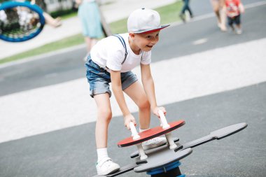 Küçük çocuk oyun parkında atlı karıncaya biniyor..