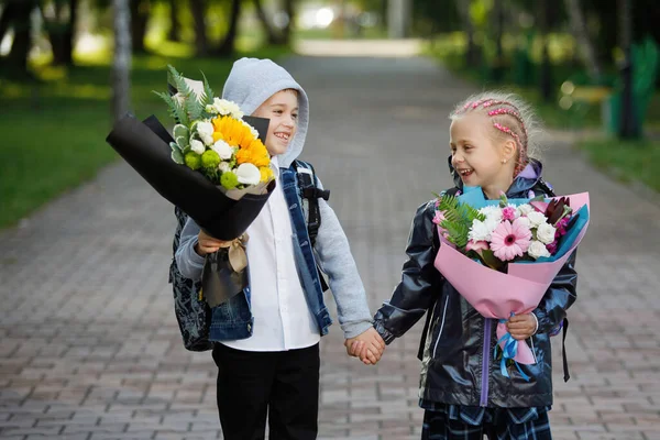 开学伊始 在一个城市公园里 学生们 一个男孩和一个女孩 手里拿着一束鲜花 第一次坐头等舱 — 图库照片