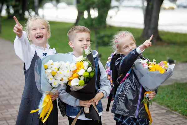 学生们 一个男孩和一个女孩 在学年开始的时候 手里拿着一束鲜花 走在城市公园里 第一次坐头等舱 — 图库照片