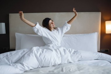 Beyaz cüppeli kadın uyandı ve sabah otel odasında uzandı..