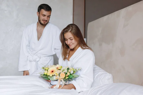 长胡子的男人把一束花送给躺在白色床上的女人 早上好 浪漫游戏 爱情礼物 — 图库照片