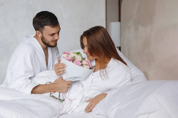 Homem Barbudo Buquê Flores Para Uma Mulher Uma Cama Branca — Fotografia de Stock