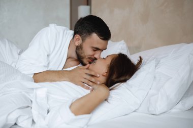 İkisi yatakta. Sakallı bir adam uyuyan bir kadını öper..