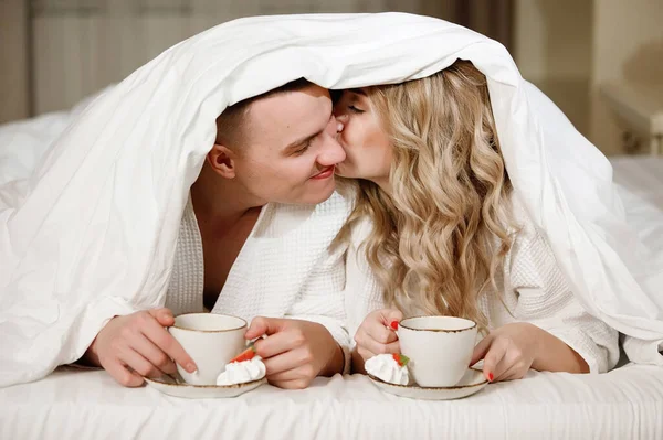 Para Pod Kołdrą Filiżanką Kawy Łóżku Kochankowie Uśmiechają Się Cieszą — Zdjęcie stockowe