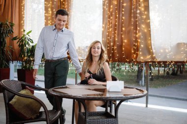 Bir erkek ve bir kadın bir kafede bir masaya otururlar.