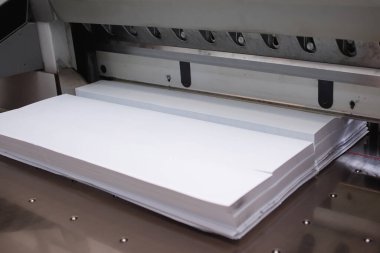 Matbaada giyotin bıçağıyla kağıt yığınları kesiyor..