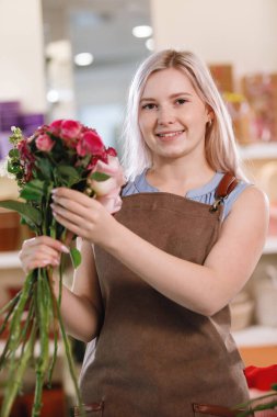 Çiçekçinin atölyesinde önlüklü sarışın kadın. Seçici odak.