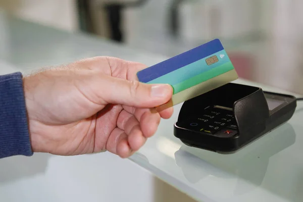 The process of paying with a contactless bank card with a plastic card in the store terminal.