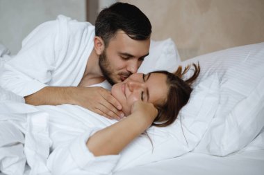 İkisi yatakta. Sakallı bir adam uyuyan bir kadını öper..