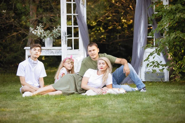 一家四口 儿子和女儿坐在草坪上的绿草上 — 图库照片