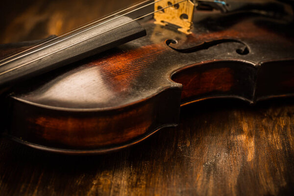 Detail of old violin in vintage style on wood background