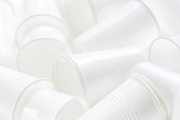 Disposable white plastic cups as background. Environmental concept. Non-compostable waste.