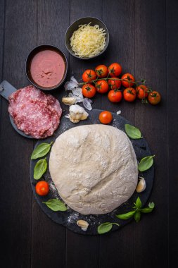 Taze hamur pizza için malzeme ve baharatlar ahşap masada. Ev yapımı yemek kavramı.