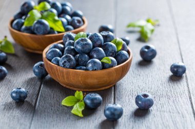 Ahşap arka planda taze organik yaban mersini kasesi. Sağlıklı yiyecek konsepti, sulu vahşi orman meyveleri..