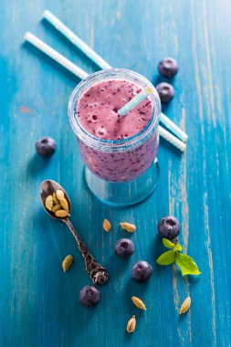 Mavi ahşap arka planda kakule ile sağlıklı yabanmersini Lassi veya smoothie içecek