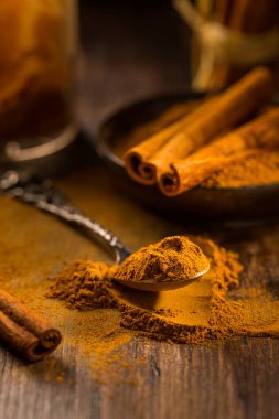 Tarçın tozu eski kaşık ve ahşap zemin üzerinde tarçın çubukları ile pişirme ve pişirme malzemesi olarak.
