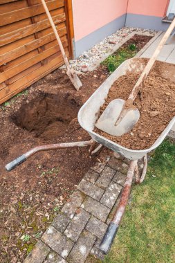 Toprak ve kürekle el arabası ağaç dikmek ya da inşaat için çukur kazıyor.