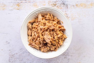 Canned tuna in a white bowl on kitchen table