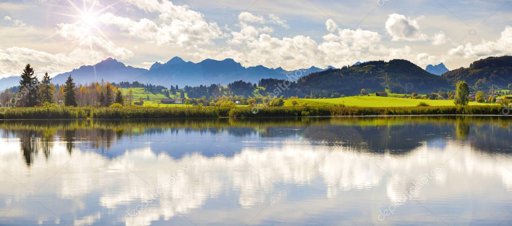  wide angle view to alps mountain range mirroring in lake Forggensee in region Allgaeu in Bavaria