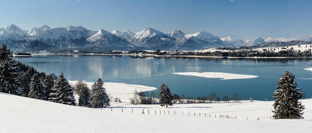panoramic landscape in Bavaria with lake and deep snow at winter
