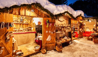 Ahşap kulübelerde aydınlatılmış dükkanlar, hediyeler ve el yapımı dekorasyonlarla romantik Noel pazarı..