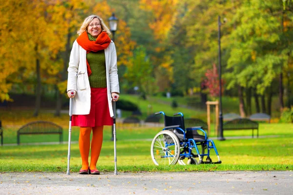 Kvinna Som Tränar Kryckor Grön Park Och Rullstol Stående Bakgrunden — Stockfoto