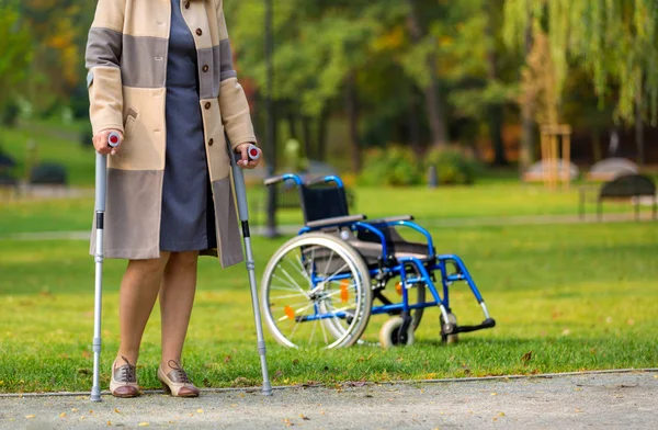 Mujer Mayor Practicando Caminar Sobre Muletas Parque Otoñal Con Silla — Foto de Stock