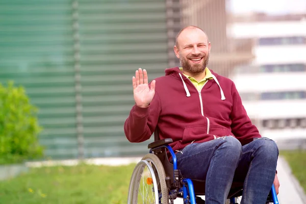 Tekerlekli sandalye sallayarak üzerinde mutlu adam — Stok fotoğraf