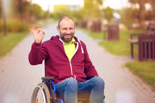 Tamam gösterilen tekerlekli sandalye üzerinde mutlu adam — Stok fotoğraf