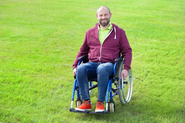 Mutlu adam tekerlekli sandalye üzerinde yeşil çim çevrili — Stok fotoğraf