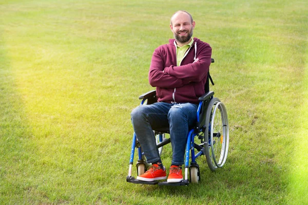 Mutlu adam tekerlekli sandalye üzerinde yeşil çim çevrili — Stok fotoğraf
