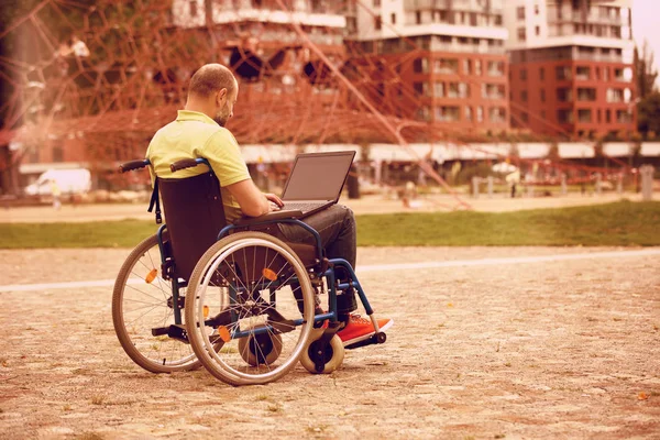 Człowiek na wózku działa na laptopie — Zdjęcie stockowe