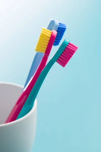 Kupası Mavi Arka Plan Üzerinde Renkli Diş Fırçaları — Stok fotoğraf