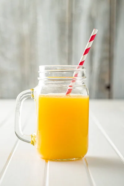 Orange juice in jug with swirly straw. — Stock Photo, Image