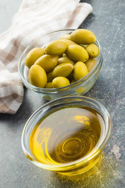 Olive verdi e olio d'oliva in ciotola di vetro. — Foto Stock
