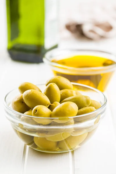 Aceitunas verdes y aceite de oliva en un recipiente de vidrio. — Foto de Stock