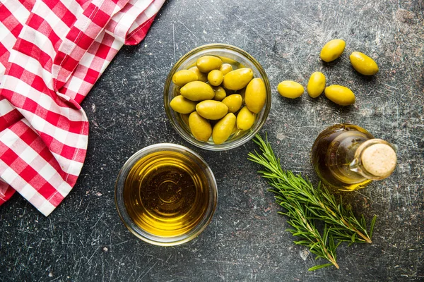 Grüne Oliven und Olivenöl in Glasschüssel. — Stockfoto