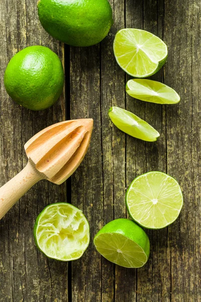 Espremedor de citrinos de madeira e limão verde. — Fotografia de Stock