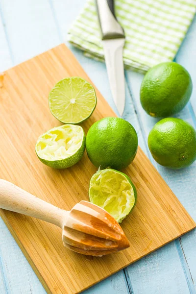 Zitrusfrüchtepresse aus Holz und grüne Limette. — Stockfoto