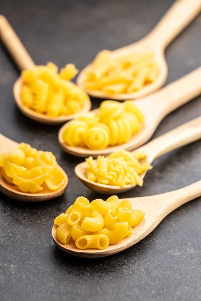 Various Types Raw Italian Pasta Wooden Spoons Black Table — Stock Photo, Image