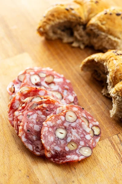 Aufgeschnittene Italienische Salami Mit Haselnüssen Und Brötchen Auf Holztisch — Stockfoto