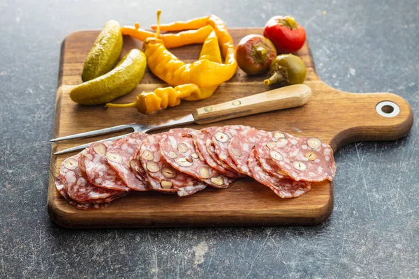 Sliced Italian Salami Hazelnuts Pickled Chili Peppers Pickles Cutting Board — Stock Photo, Image